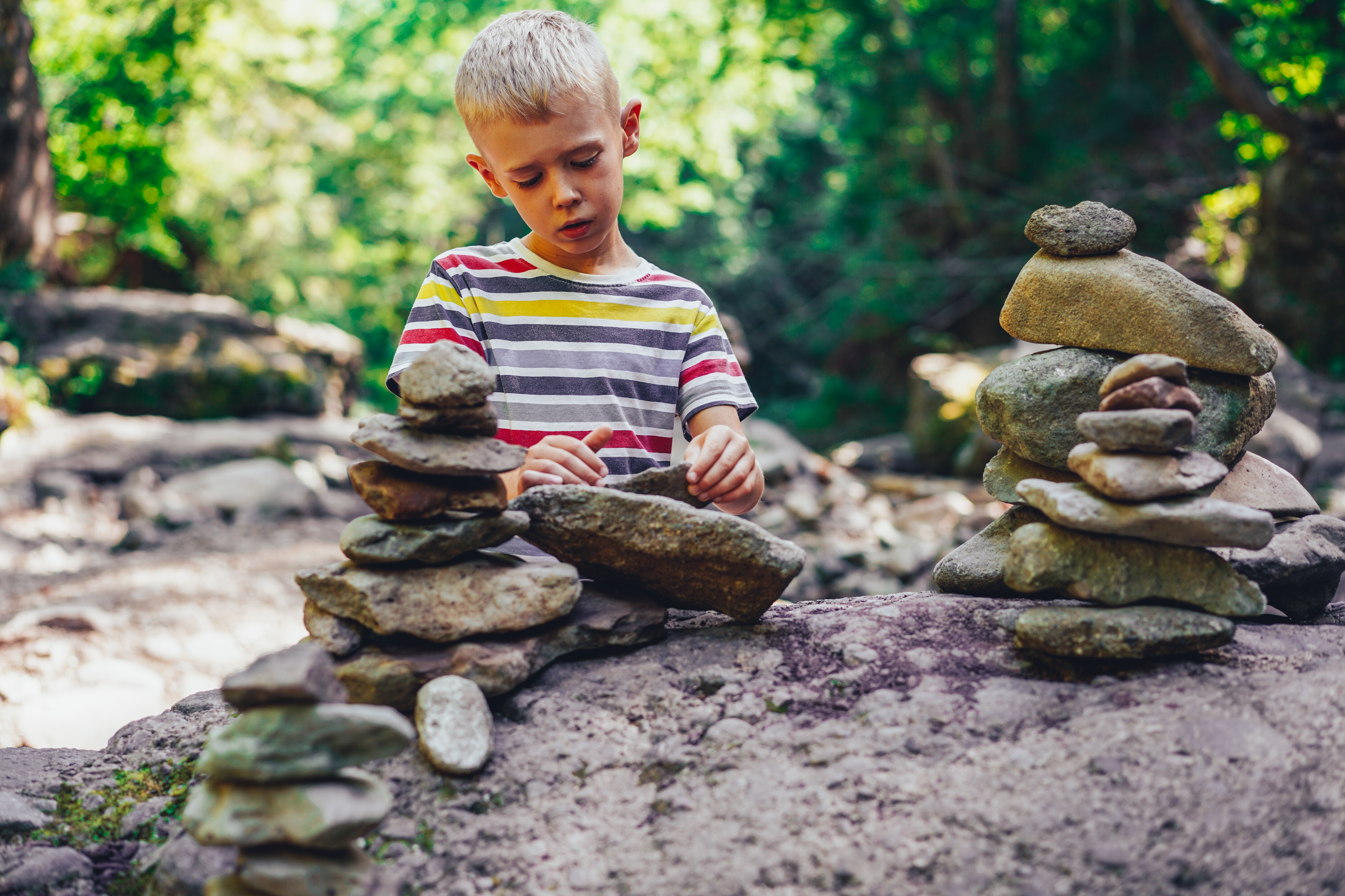 boy stacking rocks in forest
